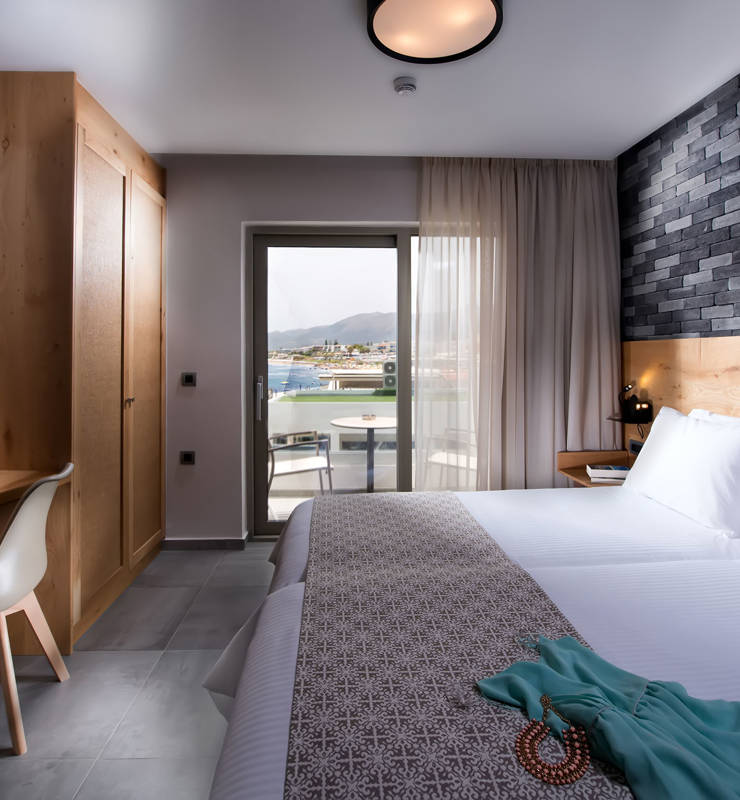 Cactus bay hotel suite with a double bed, a TV and a balcony overlooking the sea